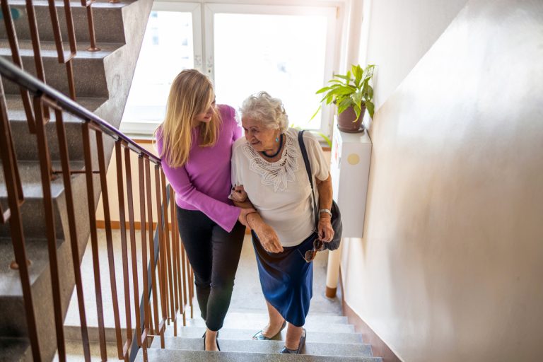 Femme aidant une personnes âgée à monter les escaliers